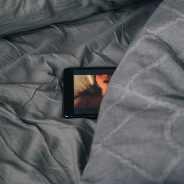 Ein Handy im Schlafzimmer zum Thema Pornosucht